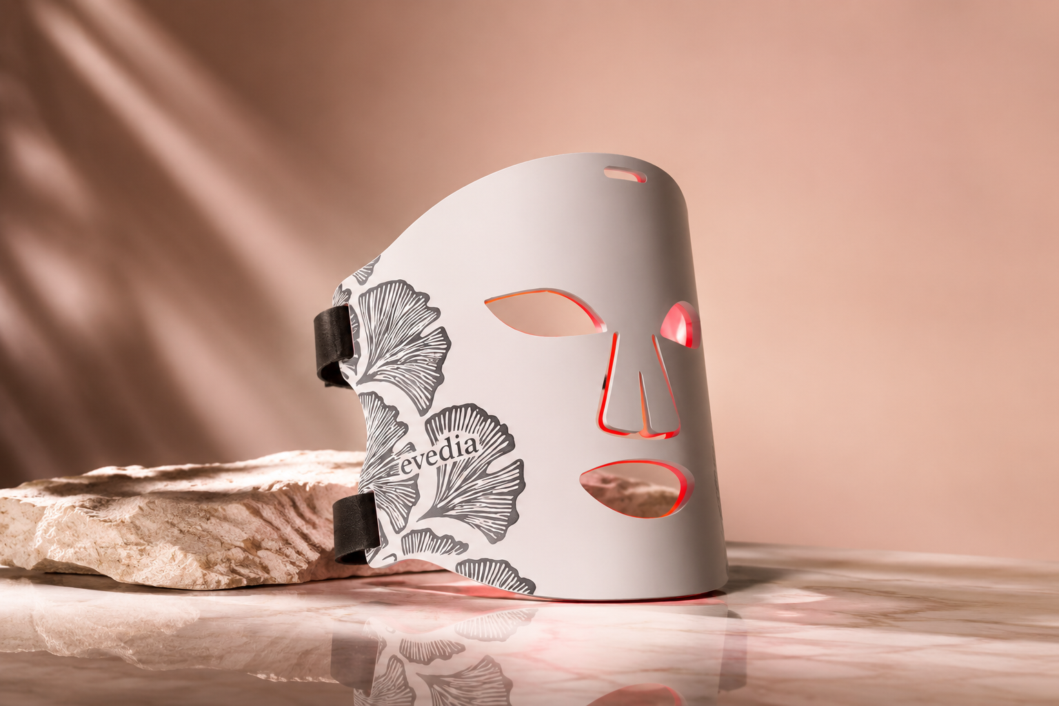 Evedia LED light therapy mask glowing on a stone plinth